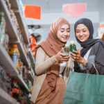 Two Muslim girls observing halal items while shopping together in a store