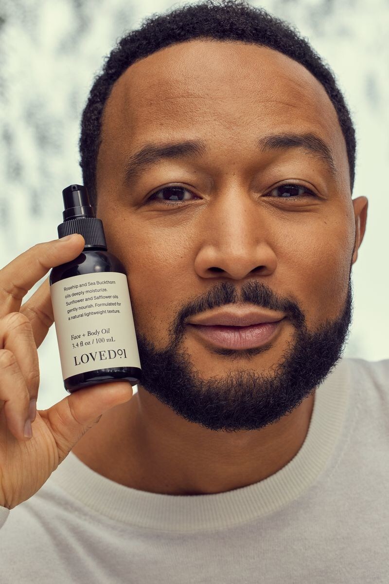 John Legend pictured with the Loved01 Face + Body Oil, now available on QVC. Image source: QVC/Loved01